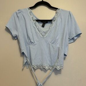 Light blue cropped shirt with a tie in the back and lace